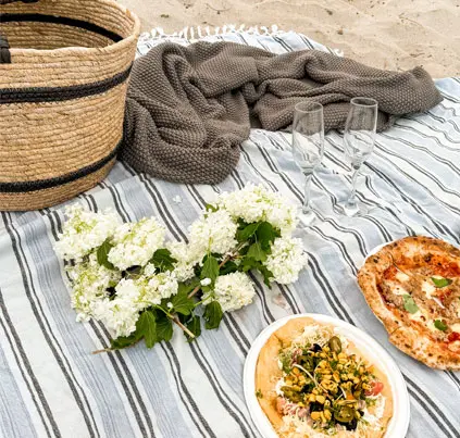 Luxury beach picnic with gourmet food, flowers and champagne glasses in Matakana, New Zealand